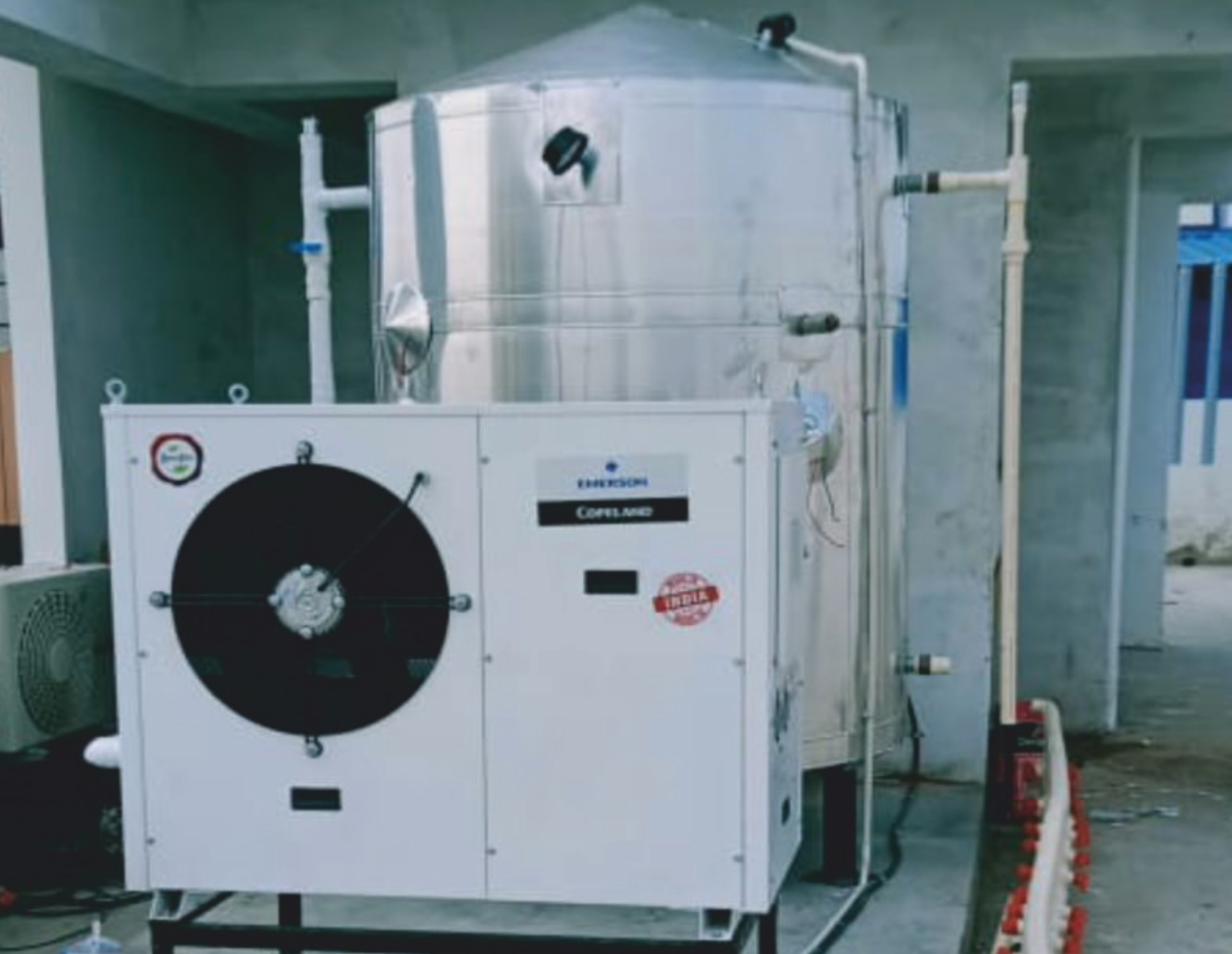 ALMIC Domestic Heat Pump unit installed beside a hot water storage tank at a residential site