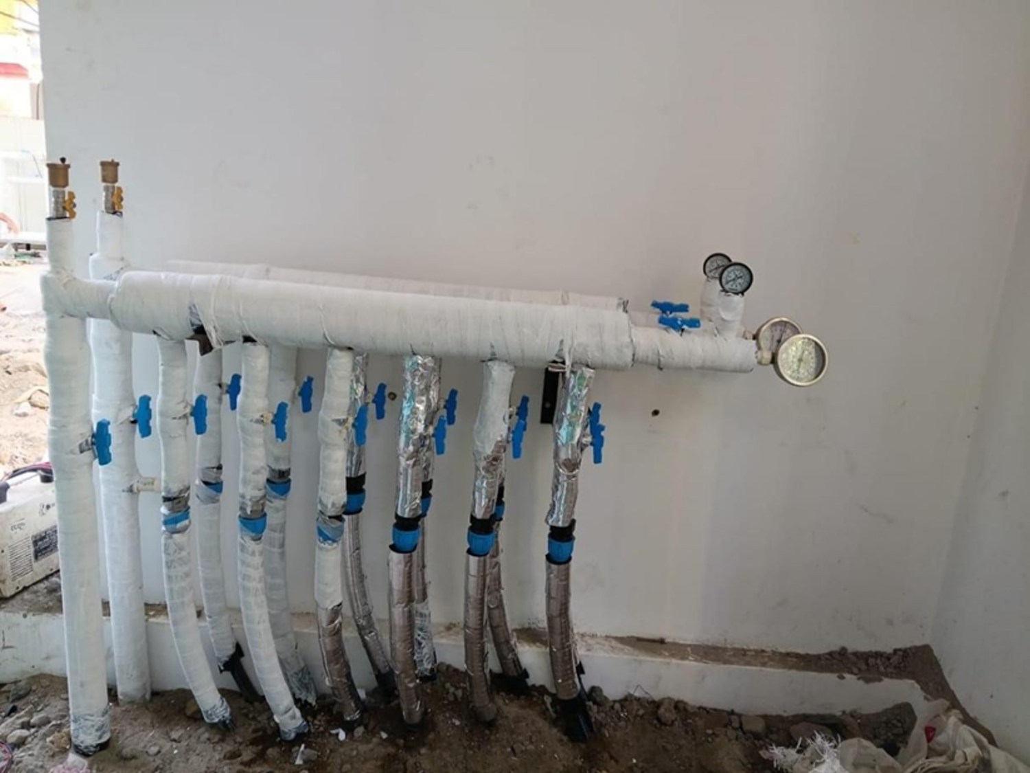 Insulated piping manifold with pressure gauges and shut-off valves at the Thiksey plant room